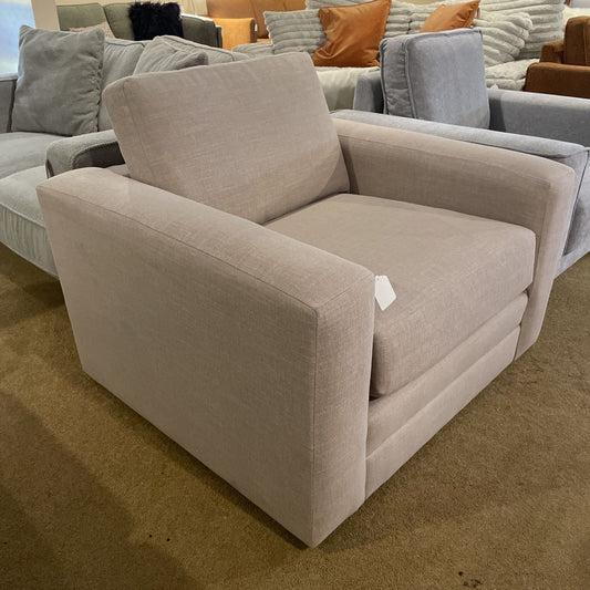 Beige armchair with a tag in a showroom setting