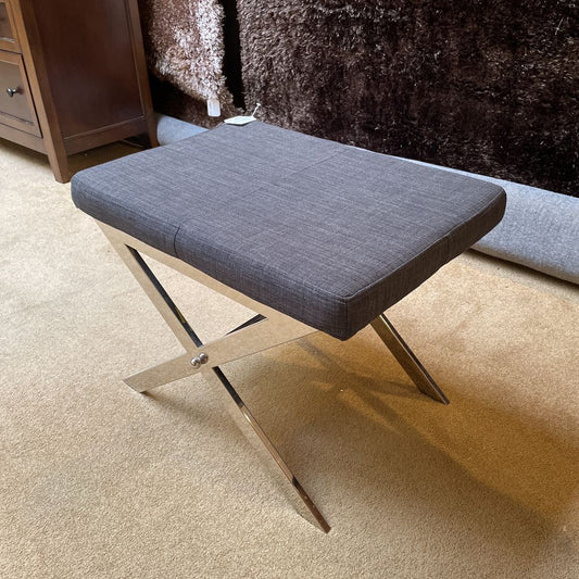 Gray cushioned bench on a carpeted floor with a wooden cabinet in the background.