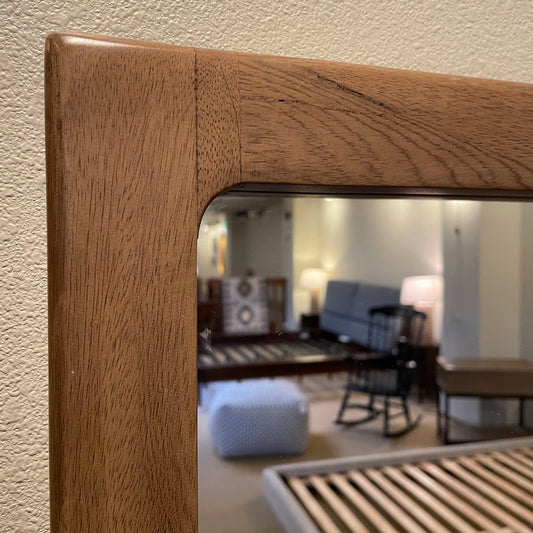 Wooden headboard with a mirror reflecting a living room.