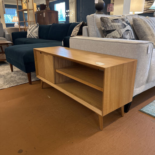 Wooden TV stand in a living room setting with a gray sofa and blue armchair.