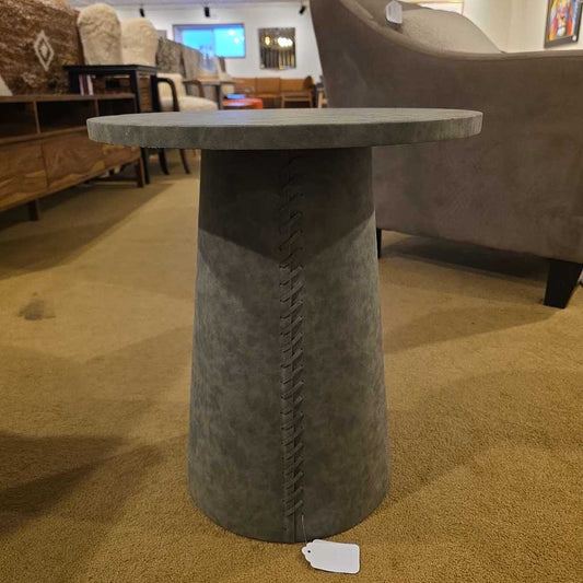 Round table with a textured base and marble-like top in a furniture store setting.