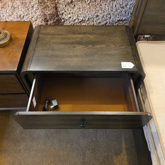 Wooden drawer unit with an open drawer displaying a small black device.