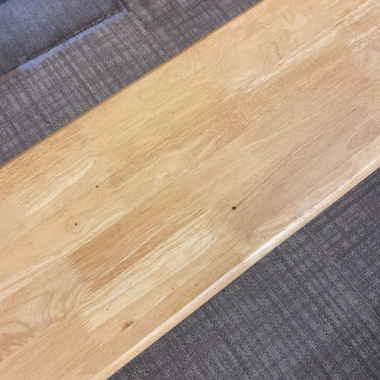 Close-up of a wooden floorboard transitioning to a gray carpet