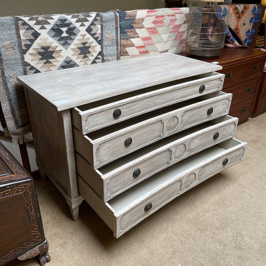 Wooden dresser with four drawers in a room setting with a patterned rug and other furniture.