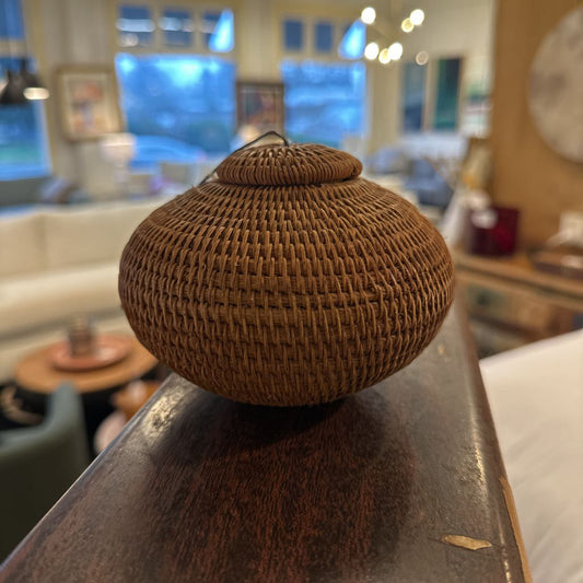 Woven brown container on a reflective surface with a blurred indoor background