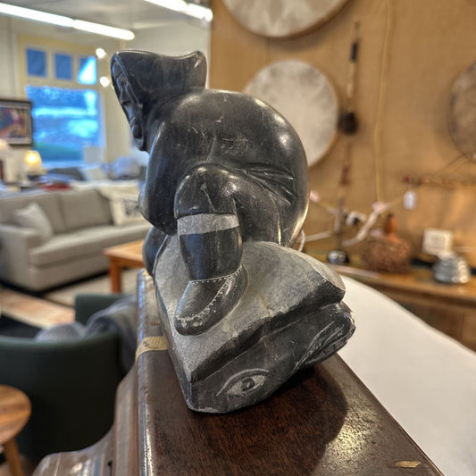 Stone sculpture of a bear on a wooden surface with a blurred indoor background