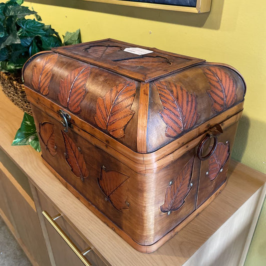 Wooden box with leaf patterns on a wooden surface