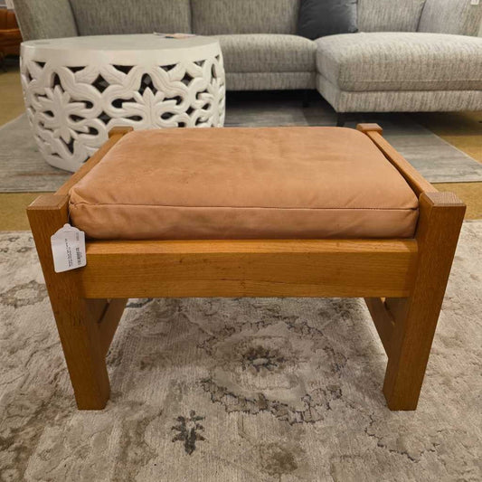 Wooden bench with a brown cushion on a patterned rug, with a white lattice table and gray sofa in the background.