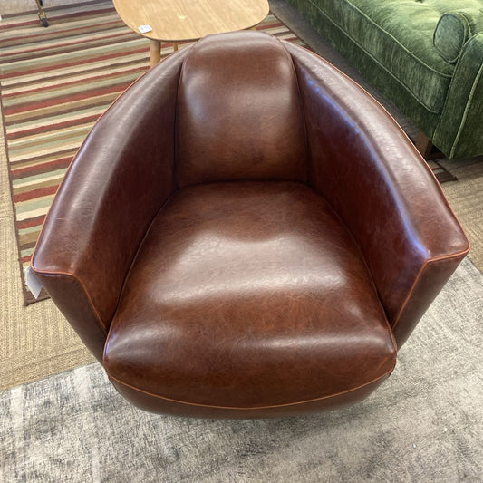 Brown leather armchair in a room with a striped rug and green sofa.