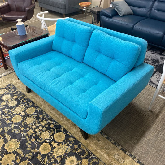 Blue sofa in a living room setting with a patterned rug and furniture.