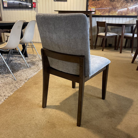 Gray upholstered chair with wooden frame on a carpeted floor