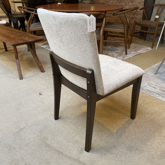 Chair with a beige cushioned backrest and dark wooden frame in a showroom setting.