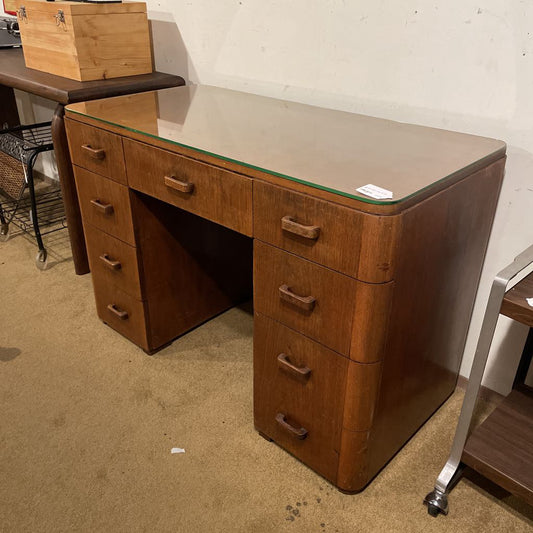 Wooden desk with glass top in a room setting