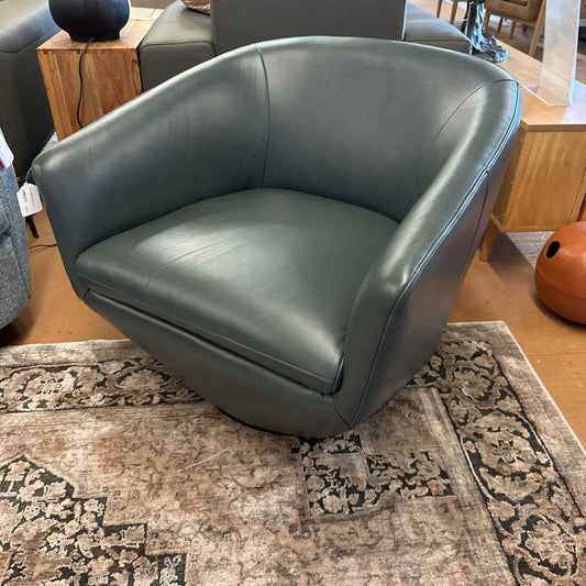 Green leather armchair on a patterned rug in a room setting
