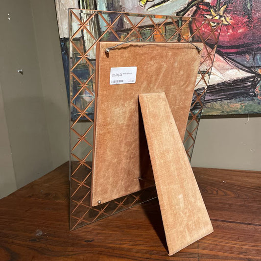 Clear glass photo frame with a textured brown back on a wooden surface.