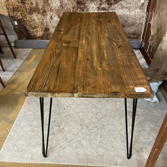Wooden table with black metal legs on a textured floor