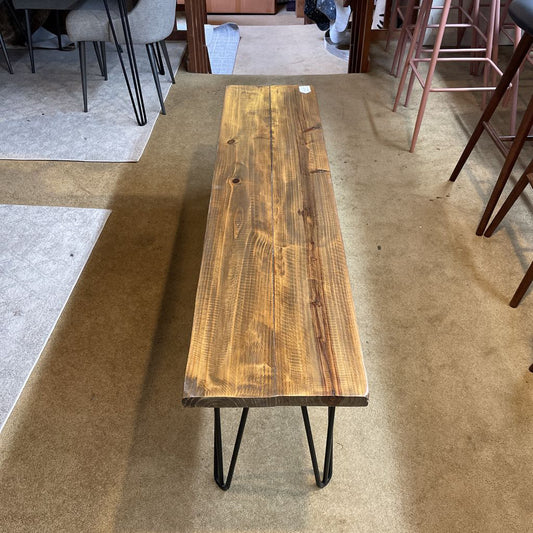 Wooden table with black hairpin legs on a carpeted floor