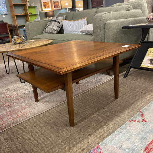 Wooden coffee table in a living room setting with a sofa and rug.