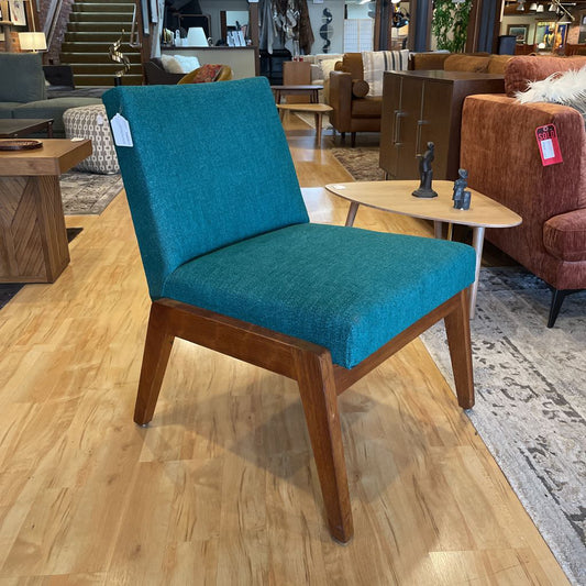 Blue chair with wooden legs on a wooden floor in a showroom setting.
