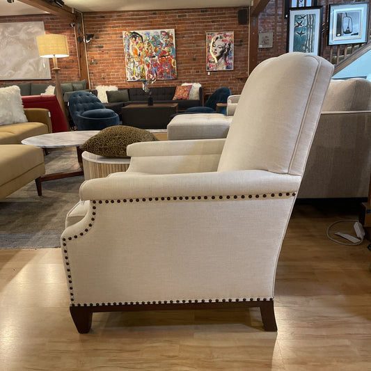 Beige armchair in a living room setting with colorful artwork on the wall.