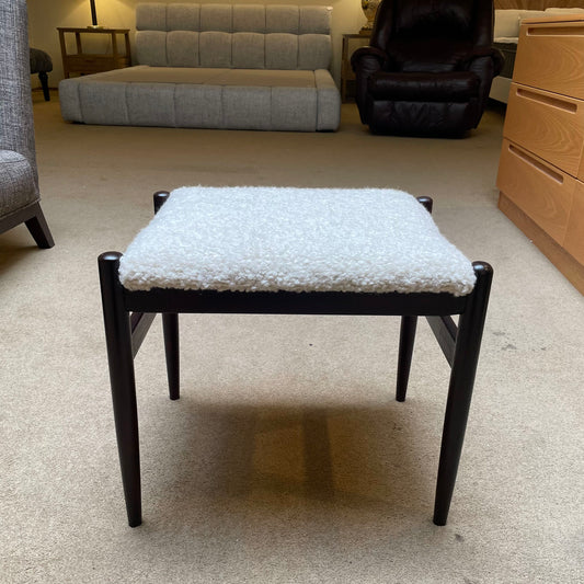 Stool with textured cushion on a carpeted floor in a room with furniture.