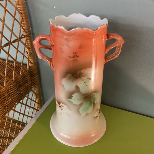 Decorative vase with floral design on a green surface and gray wall background