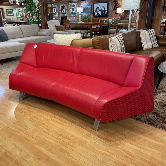 Red leather sofa in a showroom with other furniture and decor.