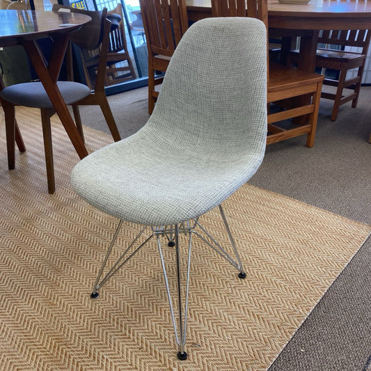 Gray chair with wireframe legs on a patterned carpet