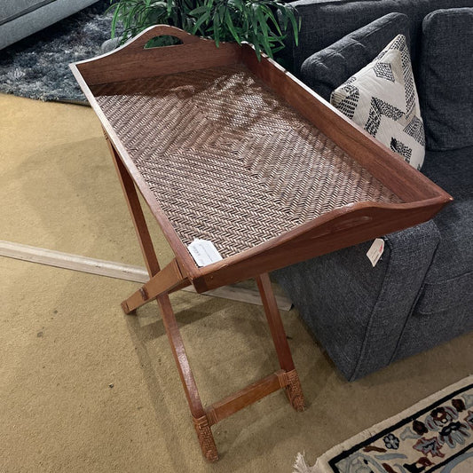 Wooden tray with woven surface on a stand in a living room setting