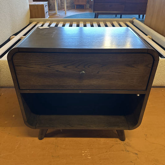Wooden nightstand with a drawer on a wooden floor.