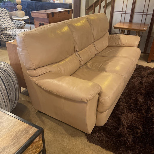 Beige leather sofa in a room with furniture and decor.