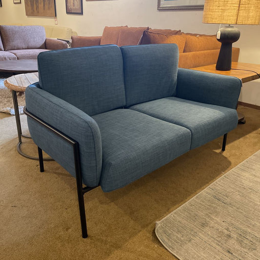 Blue sofa in a living room setting with other furniture.
