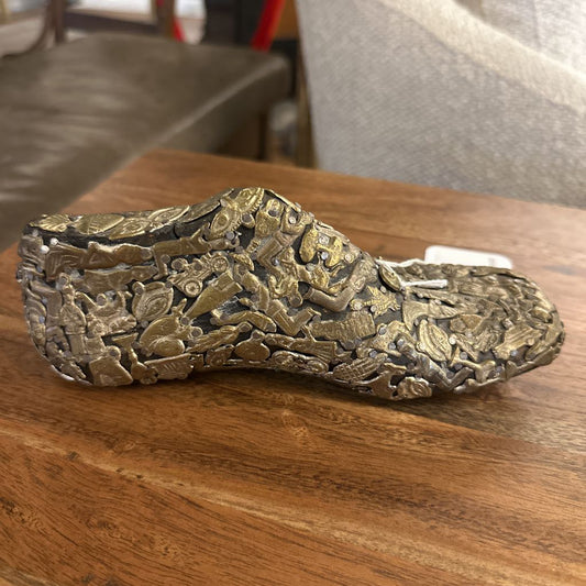 Bronze sandal with intricate designs on a wooden surface