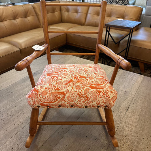 Wooden rocking chair with a patterned cushion in a furniture store setting