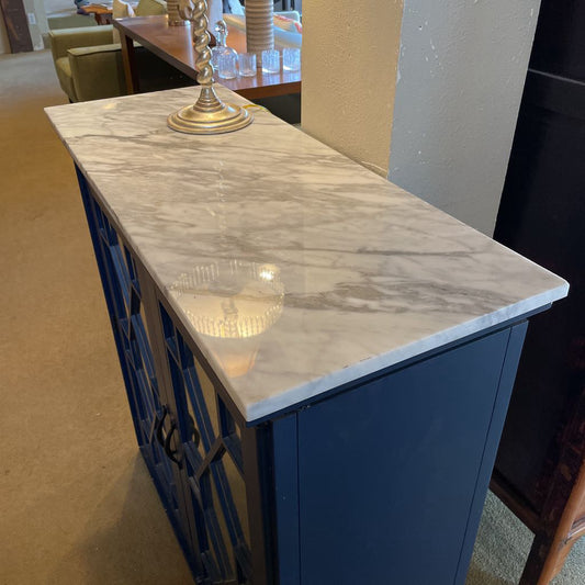 Console table with marble top and blue metal frame in a room setting