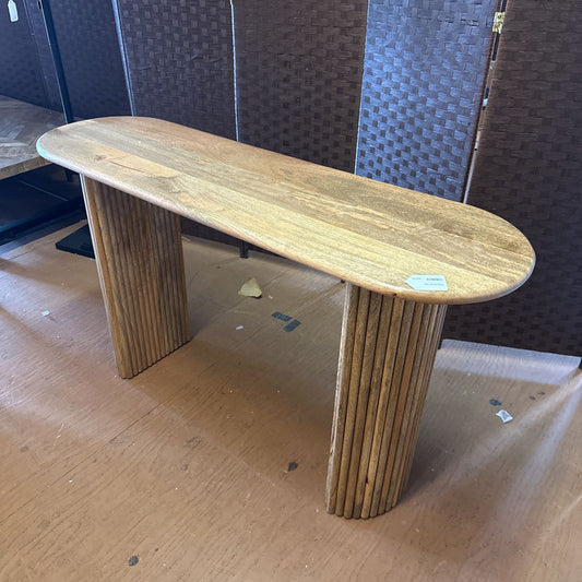 Wooden console table on a cardboard surface with a dark textured wall in the background