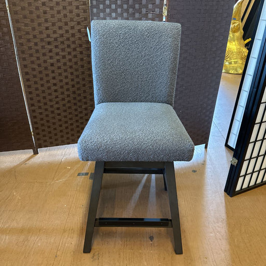 Gray upholstered chair on a wooden floor with decorative elements in the background