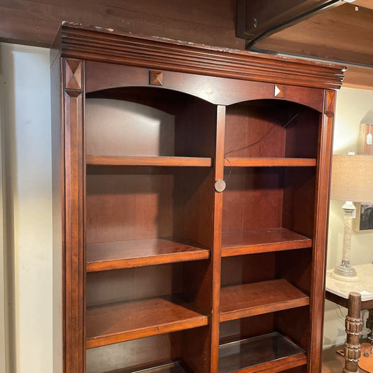 Wooden bookshelf with multiple shelves in a room setting.