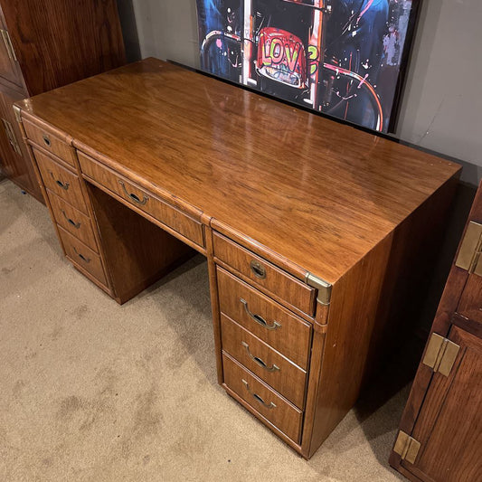 Wooden desk with multiple drawers in a room with a television in the background.