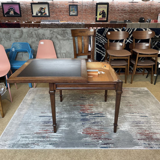 Wooden table with a metallic surface in a room with chairs and a rug.