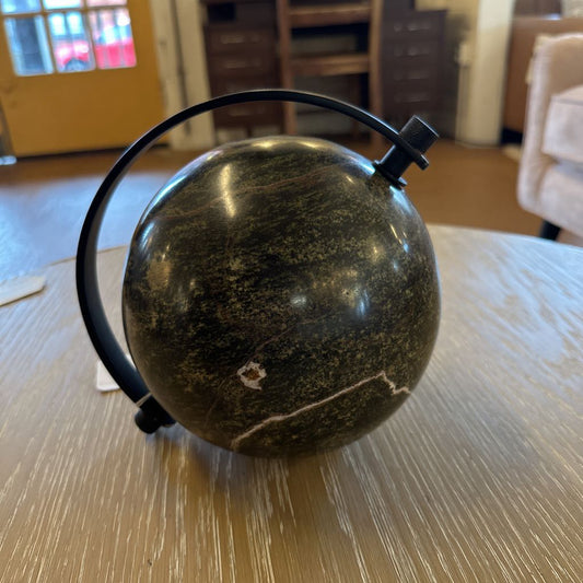 Black spherical object with a strap on a wooden surface