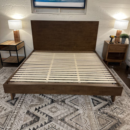 Wooden bed frame in a bedroom setting with nightstands and lamps.