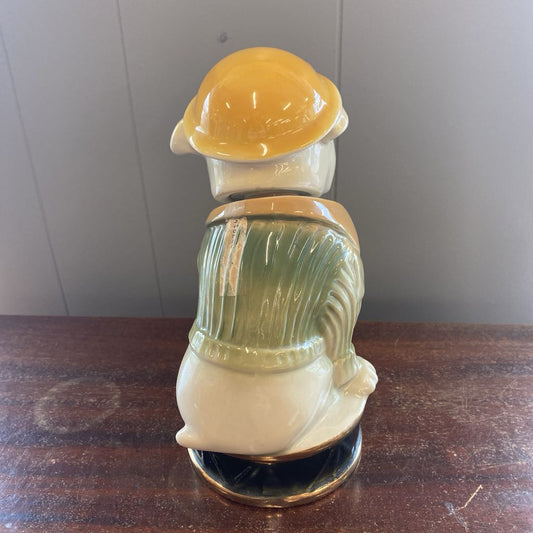Decorative ceramic piece with a yellow top and green body on a wooden surface.