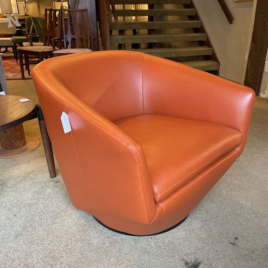 Orange leather chair in a store setting with a staircase in the background