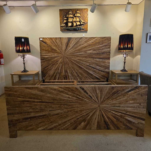 Wooden bed with starburst design in a room with lamps and wall art.