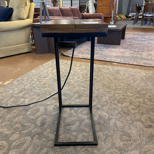 Wooden table with black metal legs on a carpeted floor in a furniture store.
