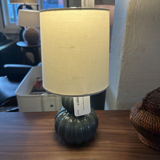 Lamp with a beige shade on a wooden surface, with a blurred indoor background