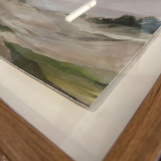 Framed landscape painting on a wooden surface