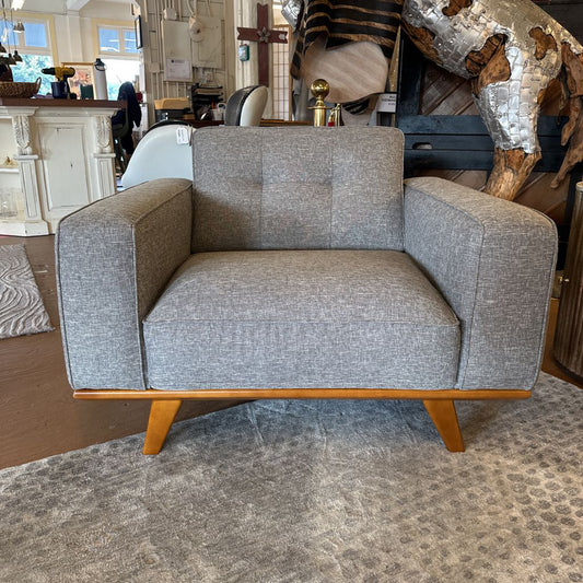 Gray upholstered armchair with wooden legs in a room setting