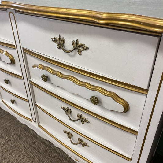 White dresser with gold accents and handles on a carpeted floor.